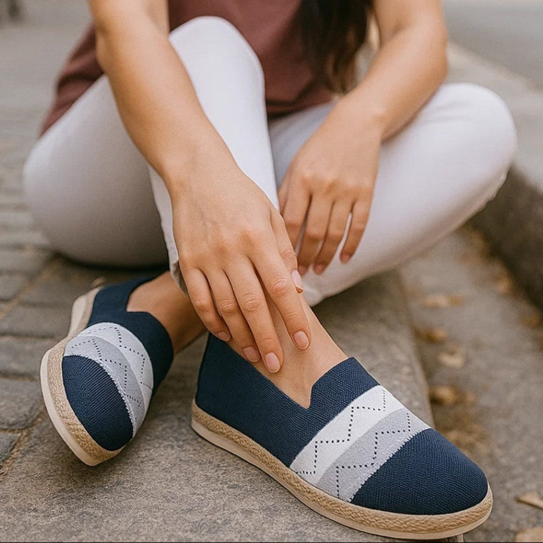 Woman wearing navy blue and gray patterned shoes sitting on a sidewalk.