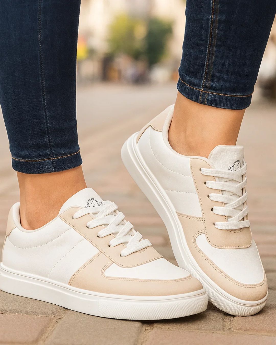 White and beige sneakers worn on a blurred street background