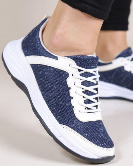 Blue sneakers with white laces on a neutral background