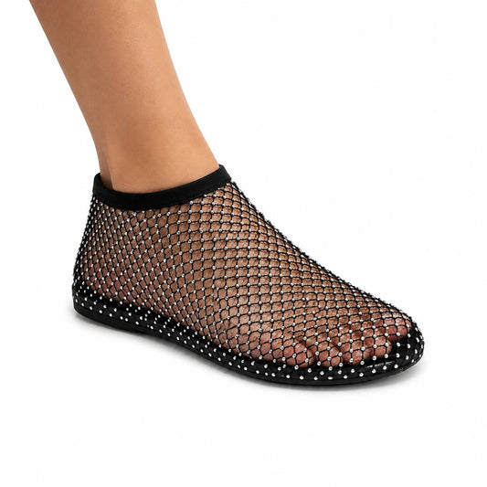 A black mesh ankle sock shoe with silver rhinestone studs, shown on a model's foot against a white background.