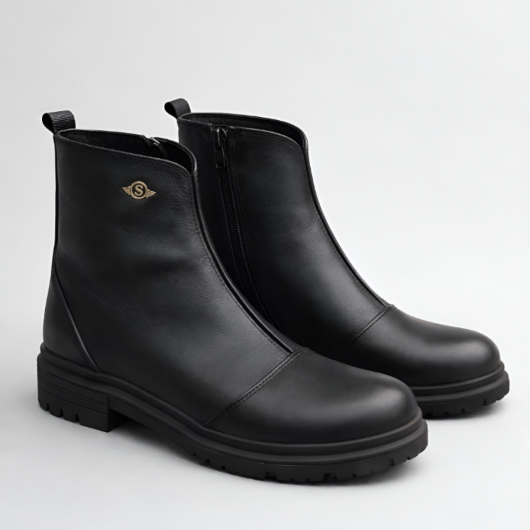 Pair of black leather boots on a light gray background