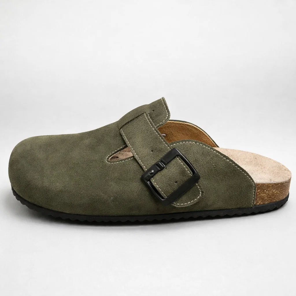 Green suede clog shoe with a black buckle on a white background